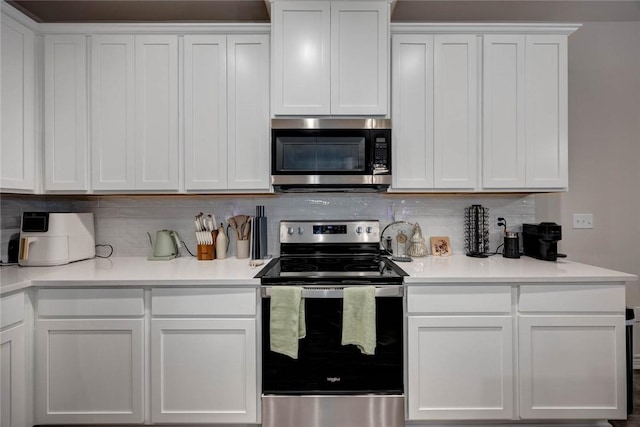 kitchen with stainless steel appliances, white cabinetry, and decorative backsplash