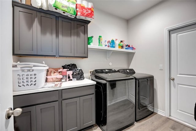 laundry area featuring washer and clothes dryer, cabinets, and light wood-type flooring