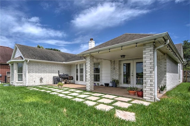 7410 Lake Micala Dr, Corpus Christi, TX 78413 - rear view of property featuring brick siding, a chimney, a lawn, roof with shingles, and a patio