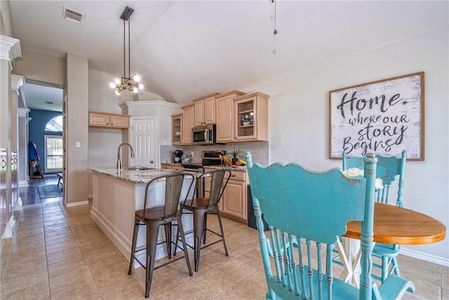 7410 Lake Micala Dr, Corpus Christi, TX 78413 - kitchen with stainless steel appliances, light brown cabinetry, decorative backsplash, light tile patterned floors, and vaulted ceiling