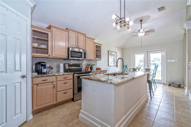 7410 Lake Micala Dr, Corpus Christi, TX 78413 - kitchen featuring stainless steel appliances, light brown cabinets, vaulted ceiling, backsplash, and light stone counters