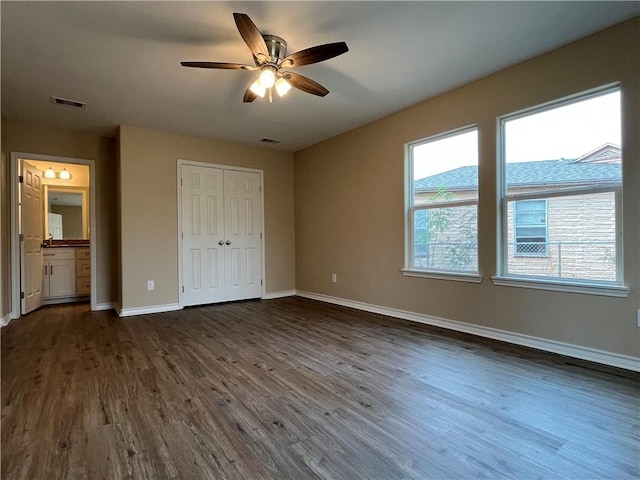 unfurnished bedroom featuring a closet, ensuite bathroom, ceiling fan, and dark hardwood / wood-style floors