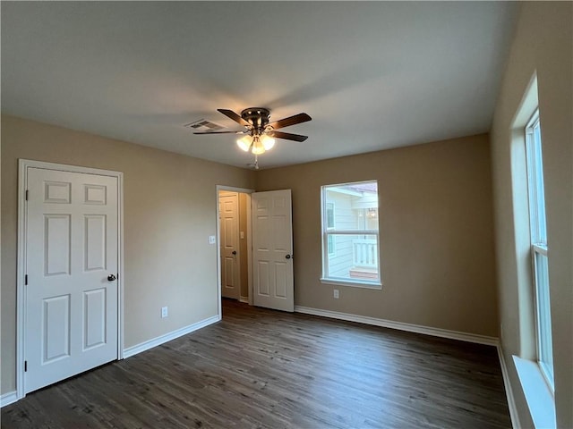 unfurnished bedroom featuring multiple windows, ceiling fan, and dark wood-type flooring