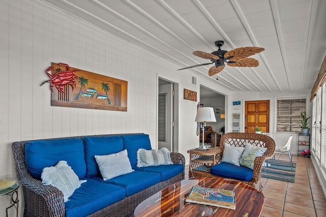 sunroom / solarium featuring beam ceiling and a ceiling fan