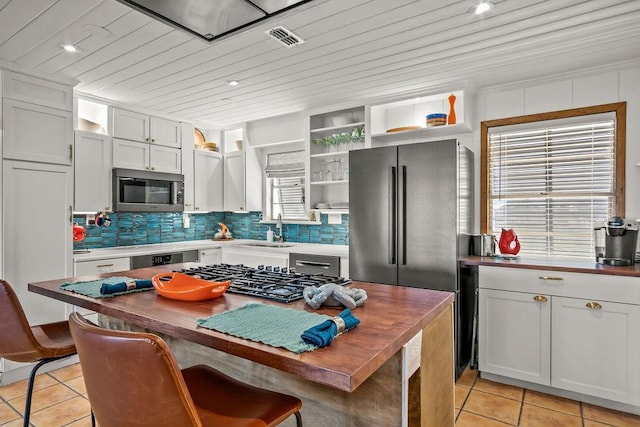 kitchen with stainless steel appliances, light tile patterned floors, white cabinets, and open shelves