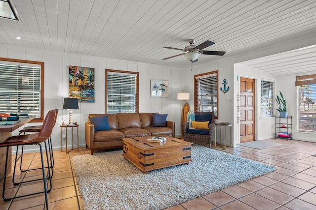 living area with light tile patterned floors, wooden ceiling, a ceiling fan, and baseboards