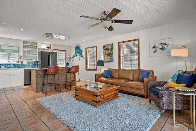 living area with wooden ceiling, plenty of natural light, ceiling fan, and light tile patterned flooring