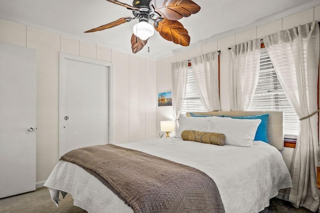 carpeted bedroom with a ceiling fan and crown molding