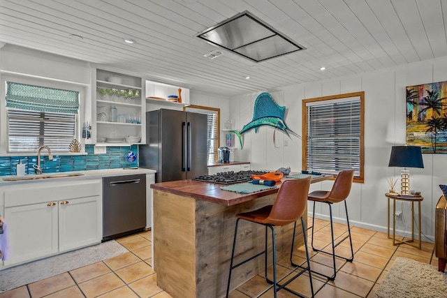 kitchen with a center island, open shelves, appliances with stainless steel finishes, white cabinets, and a sink