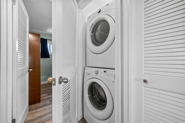 laundry room with stacked washer / drying machine and light hardwood / wood-style flooring