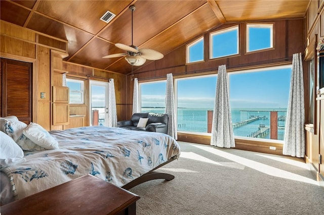 bedroom with carpet, ceiling fan, wooden walls, a water view, and wooden ceiling