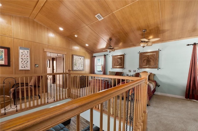 hallway with carpet floors, vaulted ceiling, wood walls, and wood ceiling