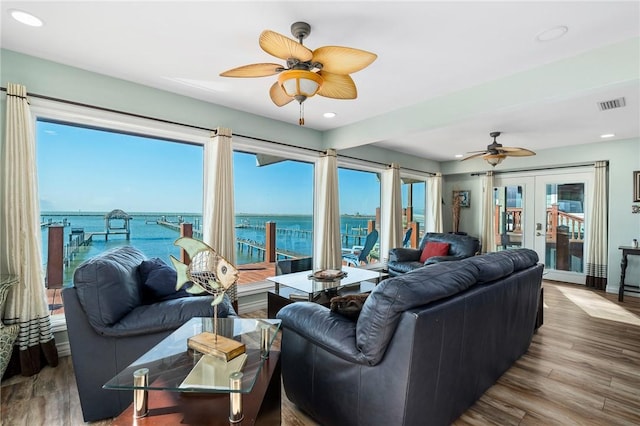 living room featuring ceiling fan, french doors, a water view, and hardwood / wood-style floors