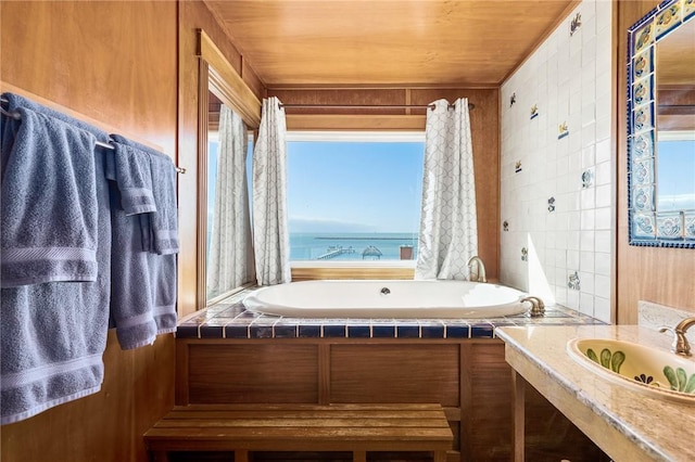 bathroom featuring vanity, a water view, wood ceiling, and a bath