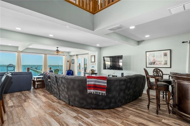 living room featuring a water view, ceiling fan, beamed ceiling, and hardwood / wood-style flooring