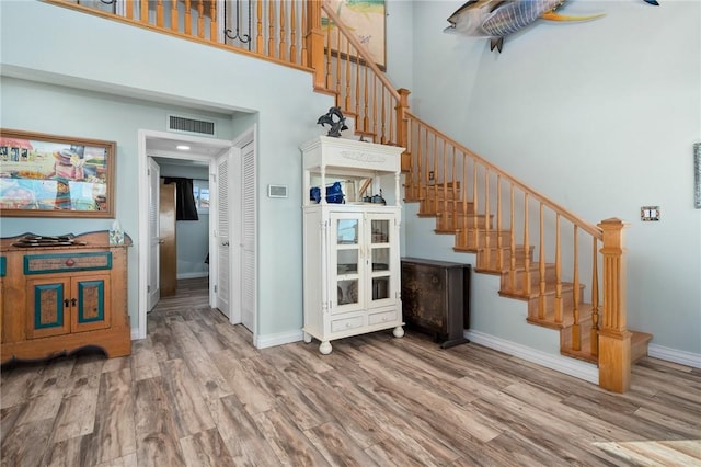 stairs featuring hardwood / wood-style floors and a high ceiling