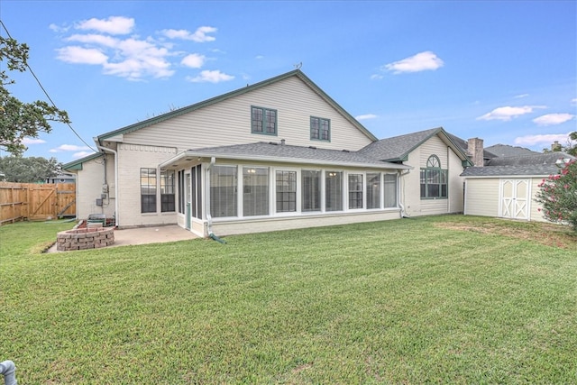 rear view of property with a patio, a lawn, a sunroom, and an outdoor fire pit