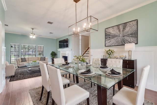 dining room with hardwood / wood-style floors, ceiling fan with notable chandelier, and crown molding