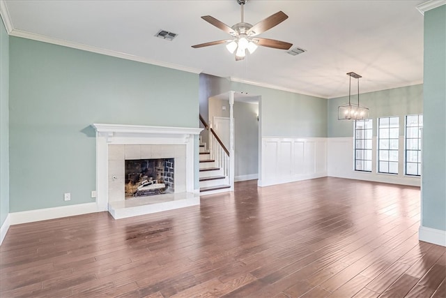 unfurnished living room featuring a tiled fireplace, dark hardwood / wood-style floors, and crown molding