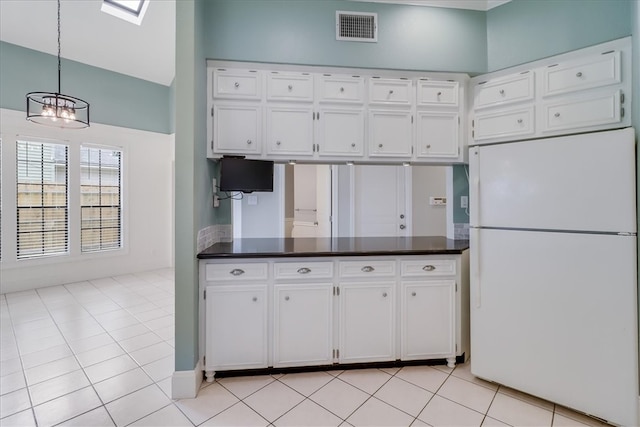 kitchen with white refrigerator, an inviting chandelier, light tile patterned flooring, and white cabinets