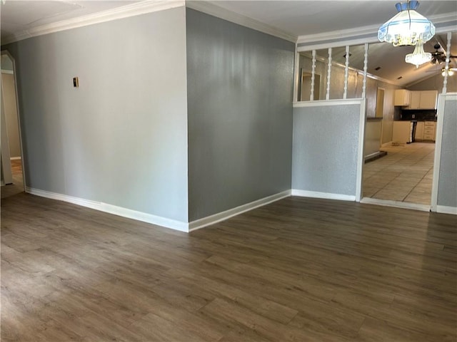 unfurnished room featuring crown molding, hardwood / wood-style floors, lofted ceiling, and an inviting chandelier