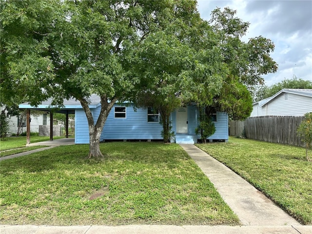 view of property hidden behind natural elements featuring a carport and a front yard