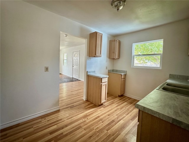 kitchen with light brown cabinetry, sink, and light hardwood / wood-style flooring