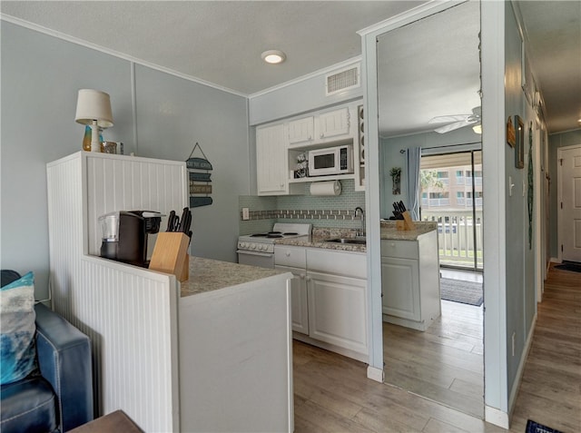 kitchen with white cabinets, sink, tasteful backsplash, light wood-type flooring, and white appliances