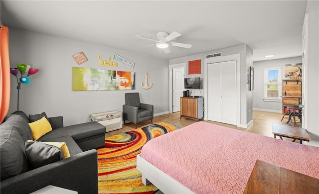 bedroom with light wood-type flooring, ceiling fan, and a closet