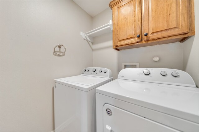 clothes washing area featuring cabinets and washer and clothes dryer