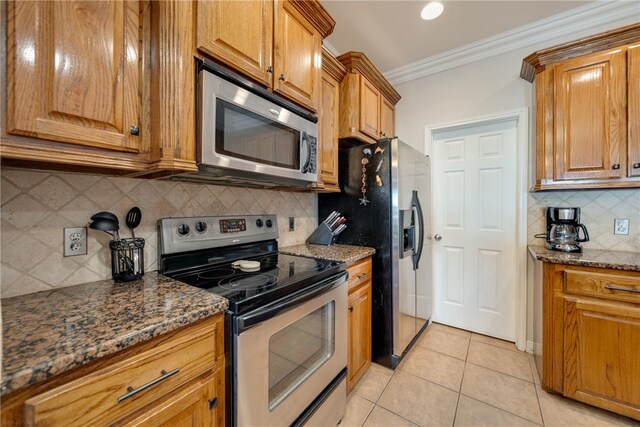 kitchen featuring decorative backsplash, appliances with stainless steel finishes, dark stone counters, and light tile patterned floors