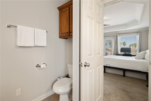 bathroom with toilet, crown molding, and a tray ceiling