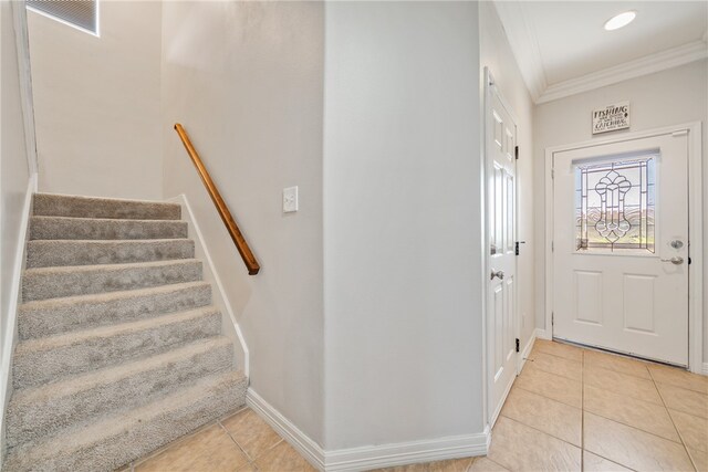 foyer entrance with light tile patterned flooring and ornamental molding