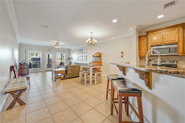 kitchen with a kitchen bar, decorative backsplash, stainless steel appliances, and ornamental molding