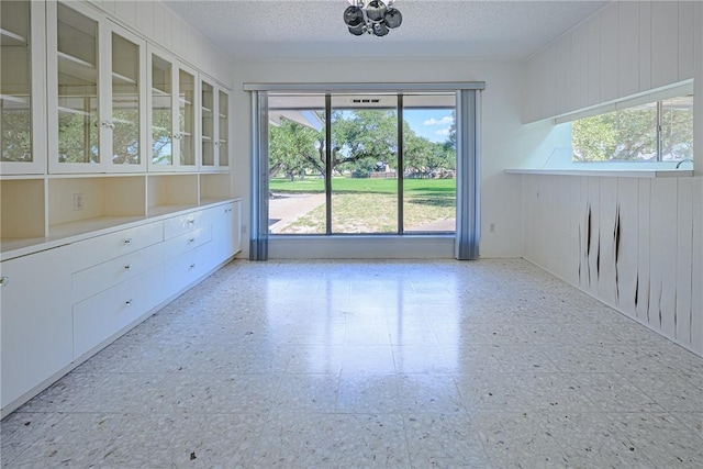 1405 Omohundro St, Rockport, TX 78382 - unfurnished dining area with light flooring, a textured ceiling, a chandelier, and wooden walls