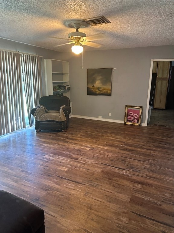 sitting room featuring dark wood-type flooring, a textured ceiling, and ceiling fan