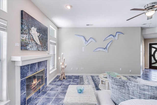 living room featuring a tile fireplace and ceiling fan