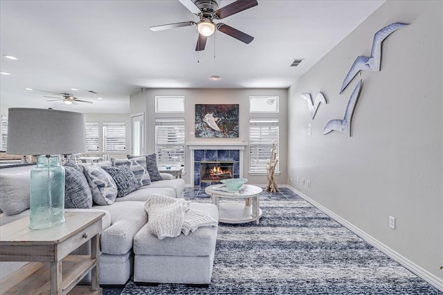 living room featuring ceiling fan and a tile fireplace