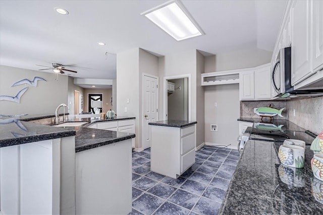 kitchen featuring backsplash, sink, kitchen peninsula, white cabinetry, and stainless steel appliances