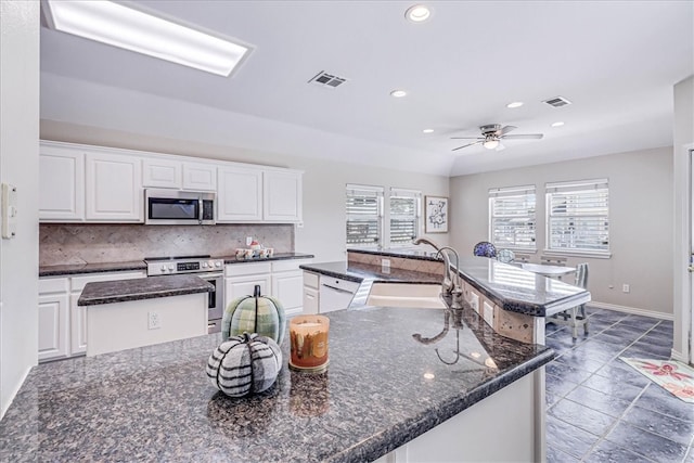 kitchen with a center island with sink, white cabinets, and appliances with stainless steel finishes