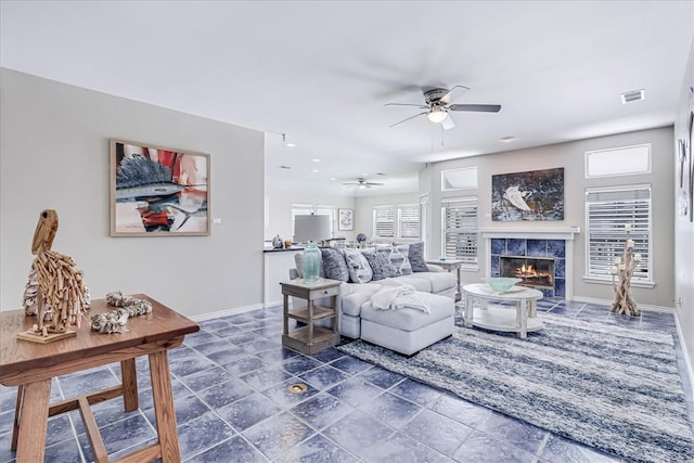 living room featuring ceiling fan, plenty of natural light, and a tiled fireplace