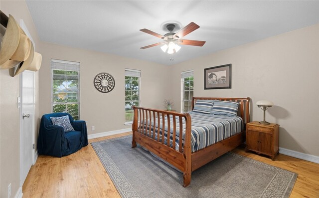 bedroom featuring multiple windows, hardwood / wood-style floors, and ceiling fan