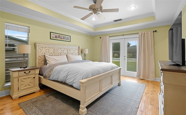 bedroom with french doors, ornamental molding, ceiling fan, a raised ceiling, and light hardwood / wood-style flooring