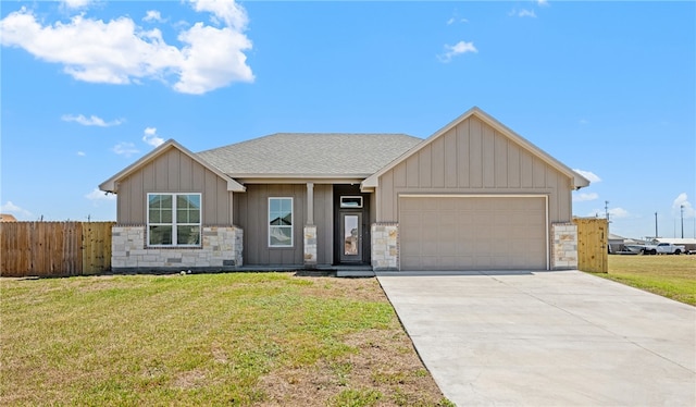 view of front facade with fence, board and batten siding, roof with shingles, a front yard, and an attached garage