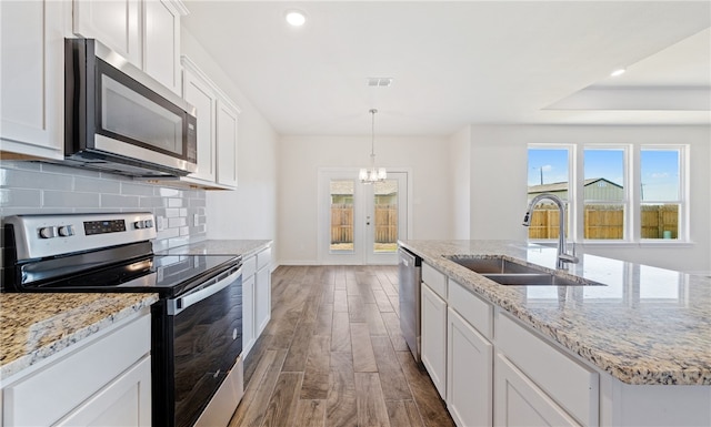 kitchen featuring dark wood-style floors, visible vents, a sink, decorative backsplash, and appliances with stainless steel finishes