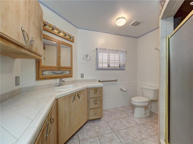 4821 Kosarek Dr, Corpus Christi, TX 78415 - bathroom featuring vanity, tile walls, a stall shower, tile patterned flooring, and wainscoting