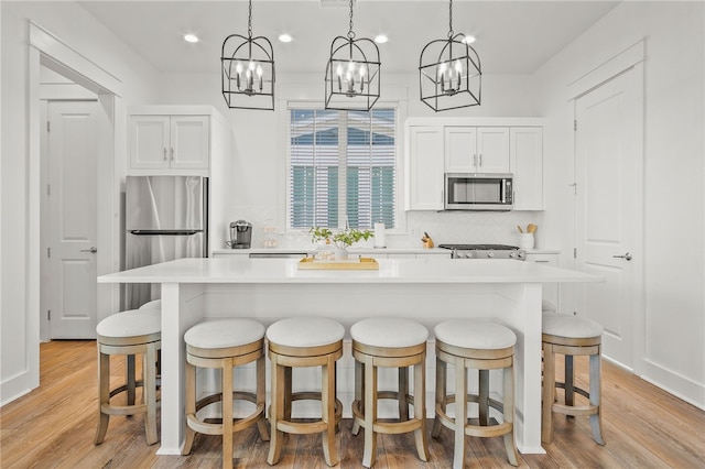 kitchen with light hardwood / wood-style flooring, white cabinetry, appliances with stainless steel finishes, and a center island