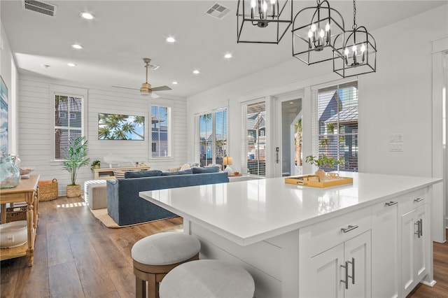 kitchen featuring white cabinetry, ceiling fan, hanging light fixtures, a kitchen island, and dark hardwood / wood-style flooring