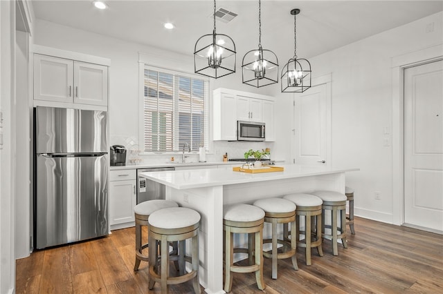 kitchen featuring dark hardwood / wood-style flooring, white cabinetry, appliances with stainless steel finishes, and a center island