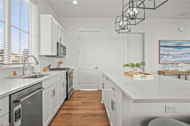 kitchen featuring pendant lighting, appliances with stainless steel finishes, dark hardwood / wood-style floors, and white cabinets